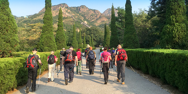 Older hikers using trekking poles on a paved mountain route in China
