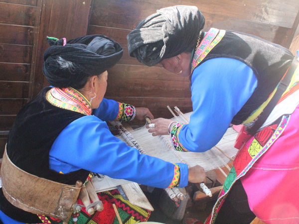 Tujia women weaving traditional Xilankapu brocade on wooden looms Tujia women weaving traditional Xilankapu brocade on wooden looms
