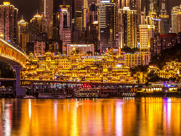 Hongya Cave buildings illuminated beside the river in Chongqing