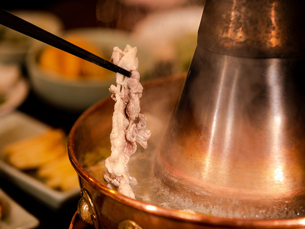 Thinly sliced lamb cooking in a traditional copper hot pot