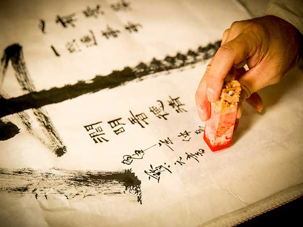 Artisan applying a carved Chinese seal to a calligraphy work