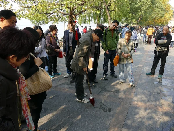 A man practicing water calligraphy beside West Lake in Hangzhou