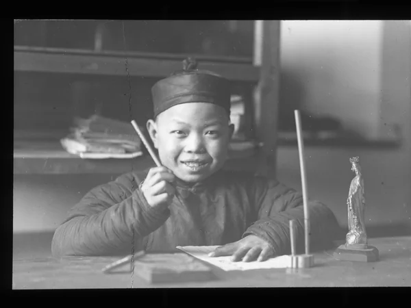 Historic photograph of a child practicing brush calligraphy at a desk