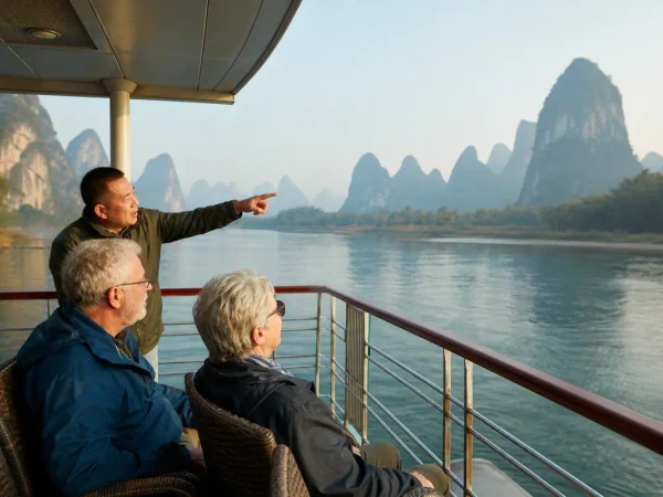 Older travelers viewing Guilin karst peaks from a shaded Li River cruise deck Older travelers viewing Guilin karst peaks from a shaded Li River cruise deck