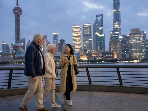 Older travelers walking with a local guide on Shanghai Bund at blue hour Older travelers walking with a local guide on Shanghai Bund at blue hour