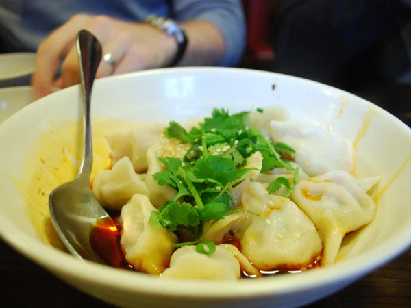Handmade pork dumplings served with red chilli oil sauce Handmade pork dumplings served with red chilli oil sauce
