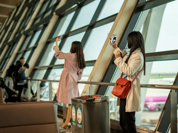 Travelers using smartphones beside the windows at Shanghai Pudong Airport Travelers using smartphones beside the windows at Shanghai Pudong Airport