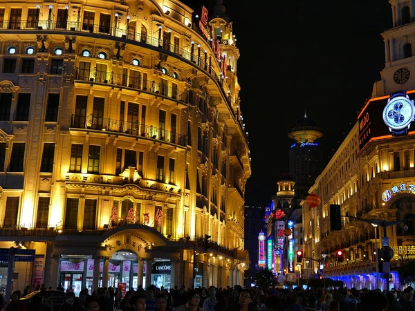 People walking along a well-lit pedestrian street in a Chinese city