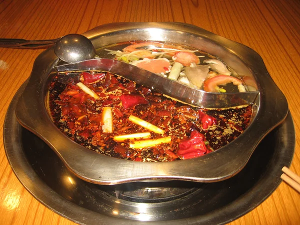 Spicy Chongqing hot pot bubbling at a restaurant table Spicy Chongqing hot pot bubbling at a restaurant table