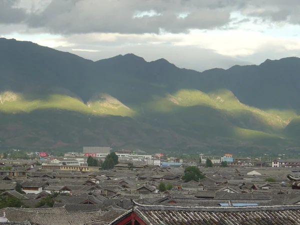 Traditional rooftops in Lijiang with mountains beyond