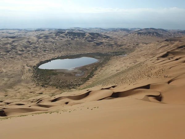 Interdunal lake surrounded by high dunes in the Badain Jaran Desert