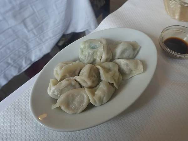 Boiled jiaozi dumplings arranged on a plate with dipping sauce Boiled jiaozi dumplings arranged on a plate with dipping sauce
