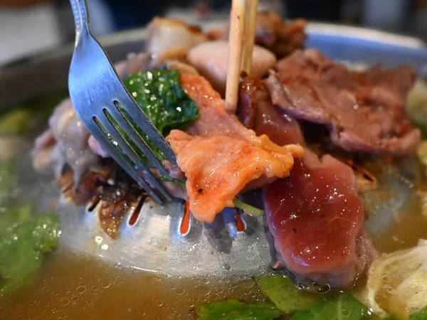 Hot-pot broth with raw ingredients ready for cooking Hot-pot broth with raw ingredients ready for cooking