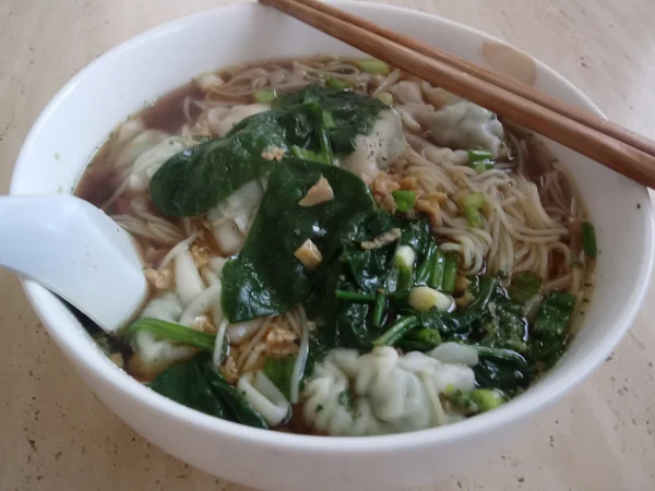 Wontons served in a clear broth with green vegetables Wontons served in a clear broth with green vegetables