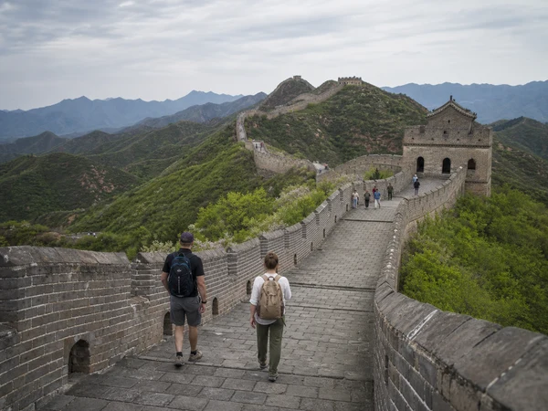 Travelers hiking a restored Great Wall section in the mountains Travelers hiking a restored Great Wall section in the mountains
