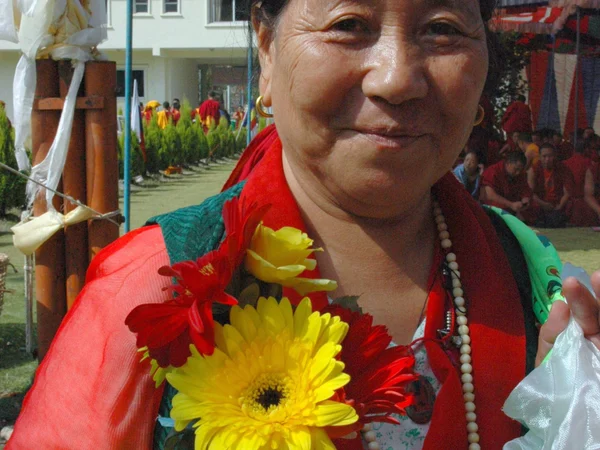 Tibetan woman carrying flower and katag offerings at a monastery courtyard Tibetan woman carrying flower and katag offerings at a monastery courtyard
