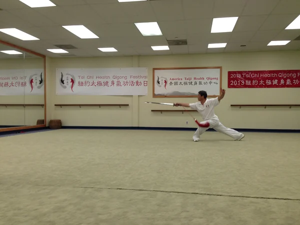 A practitioner demonstrates Health Qigong during an indoor event