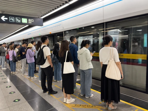 Passengers waiting behind platform markings at a modern Chinese metro station Passengers waiting behind platform markings at a modern Chinese metro station