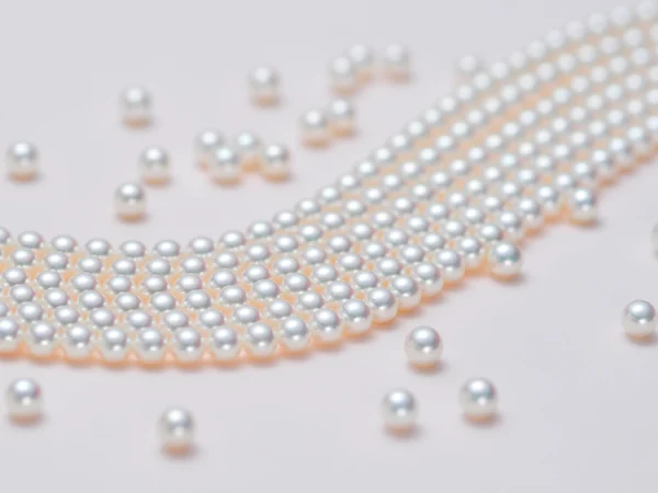 Akoya pearl necklace and loose pearls arranged on a white surface