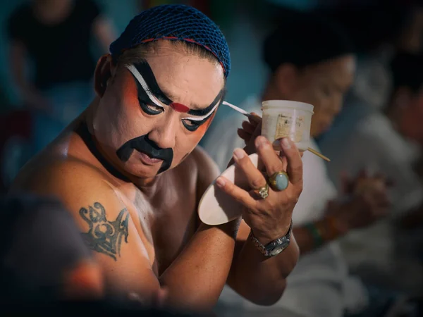 A Chinese opera performer applies stage makeup before a show A Chinese opera performer applies stage makeup before a show