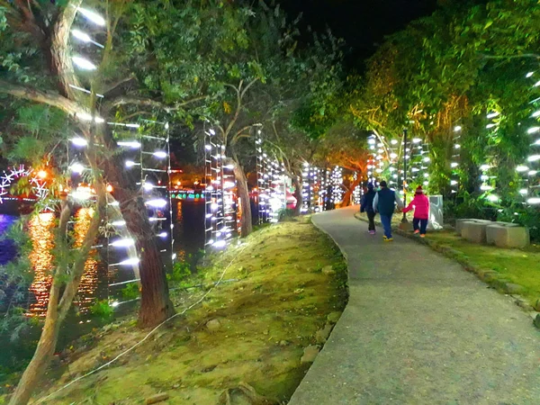 Visitors walking through an illuminated lantern installation at night Visitors walking through an illuminated lantern installation at night