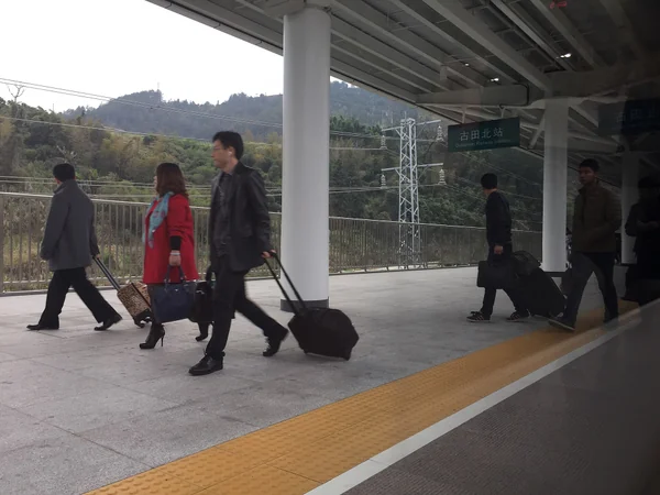 Passengers walking along a platform at a railway station in China