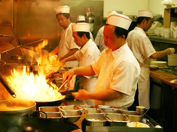 Cook preparing a hot dish over a flaming wok Cook preparing a hot dish over a flaming wok