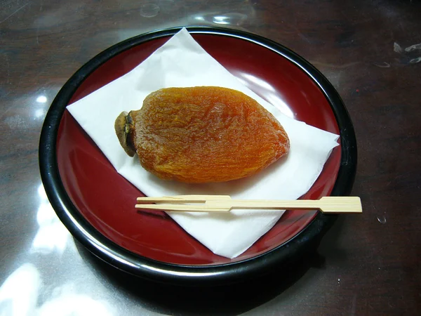 A traditional dried persimmon served on a small plate A traditional dried persimmon served on a small plate