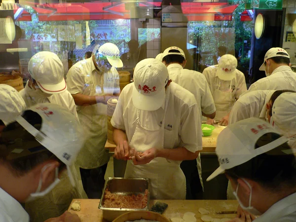 Cooks shaping Chinese dumplings by hand in a restaurant kitchen Cooks shaping Chinese dumplings by hand in a restaurant kitchen