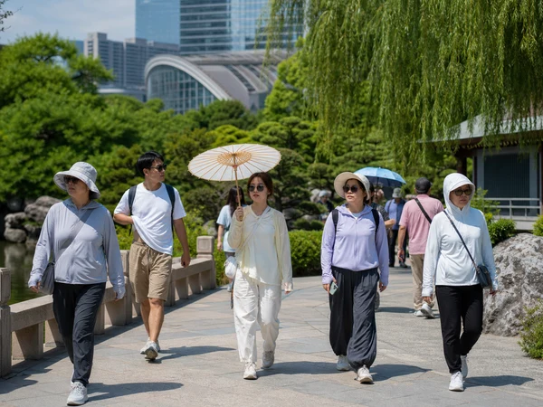 Pedestrians using parasols, hats and sleeves for sun protection in a Chinese city garden Pedestrians using parasols, hats and sleeves for sun protection in a Chinese city garden