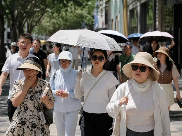 Pedestrians using parasols and hats for sun protection on a Chinese city street Pedestrians using parasols and hats for sun protection on a Chinese city street