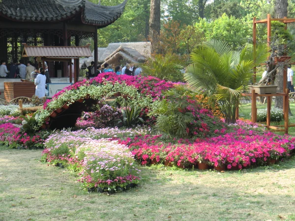 Visitors exploring a flower garden at Suzhou's Humble Administrator's Garden