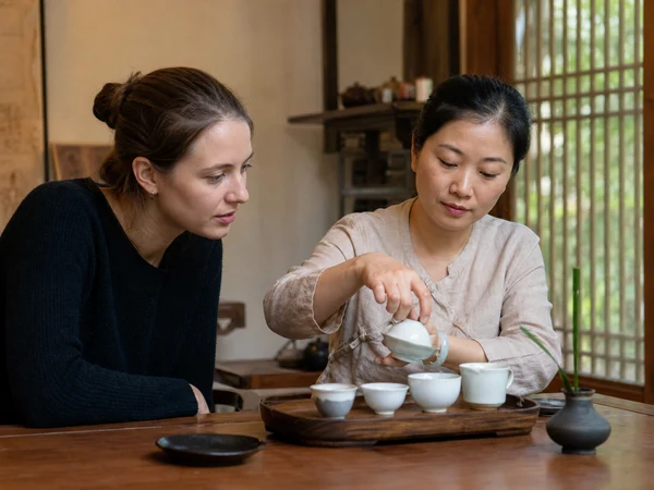 Visitor learning tea etiquette from a local teacher in a small tea room Visitor learning tea etiquette from a local teacher in a small tea room