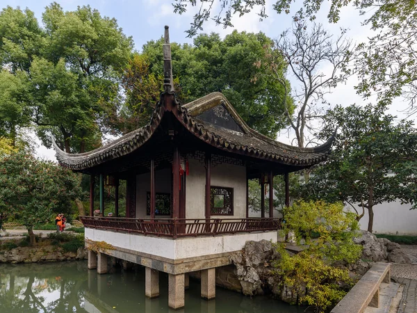 A framed garden view showing architecture, plants and visitors in Suzhou A framed garden view showing architecture, plants and visitors in Suzhou