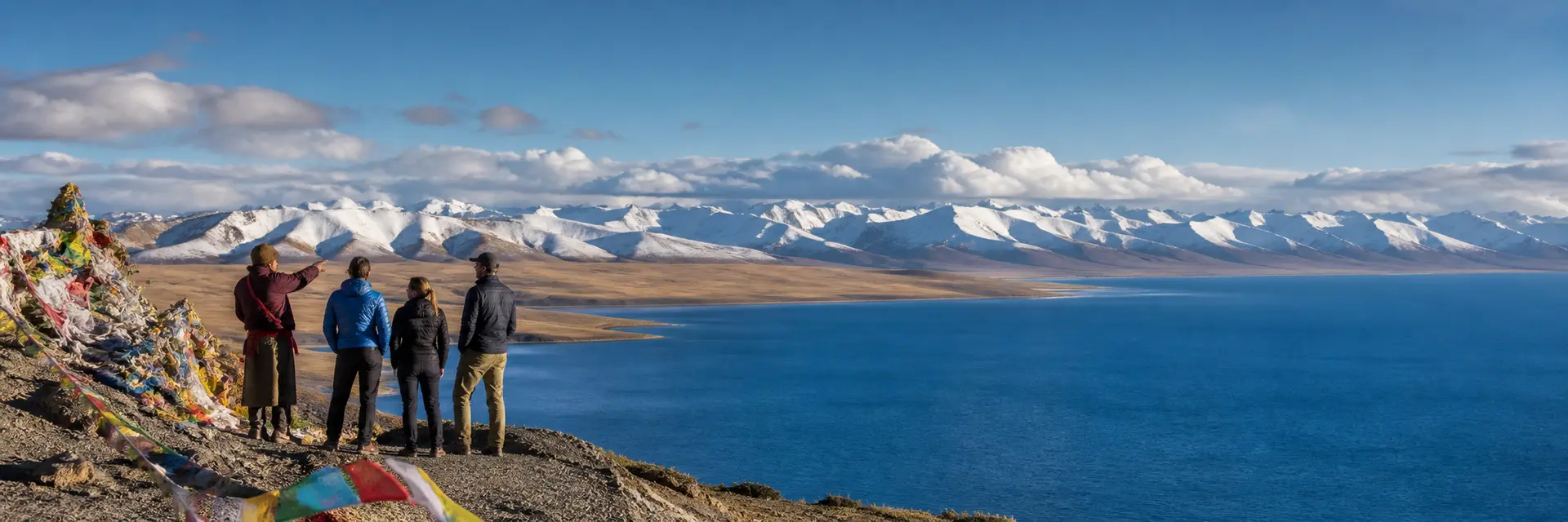 Travelers overlooking Namtso Lake and snowy mountains in Tibet