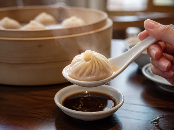 Xiaolongbao cooled on a spoon above vinegar before eating