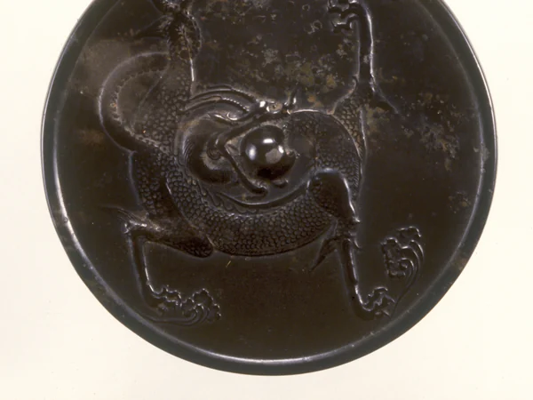A Chinese bronze mirror decorated with a dragon A Chinese bronze mirror decorated with a dragon
