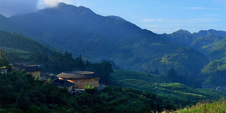 Round Fujian Tulou surrounded by mountain farms and village houses Round Fujian Tulou surrounded by mountain farms and village houses