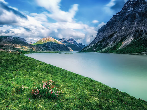 Alpine lake and green meadow beneath mountains in Tibet during spring Alpine lake and green meadow beneath mountains in Tibet during spring