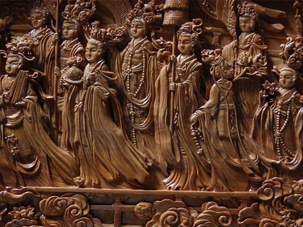 Carved Tibetan wooden relief depicting Buddhist figures and decorative motifs