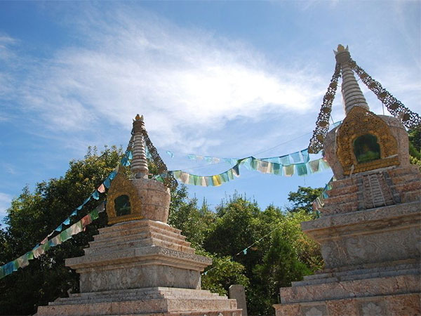 White Tibetan stupas with prayer flags beneath a blue sky White Tibetan stupas with prayer flags beneath a blue sky