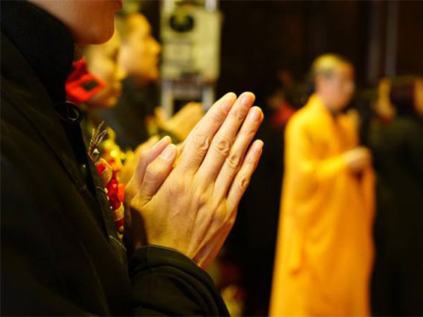 Visitor holding palms together quietly inside a Tibetan monastery Visitor holding palms together quietly inside a Tibetan monastery